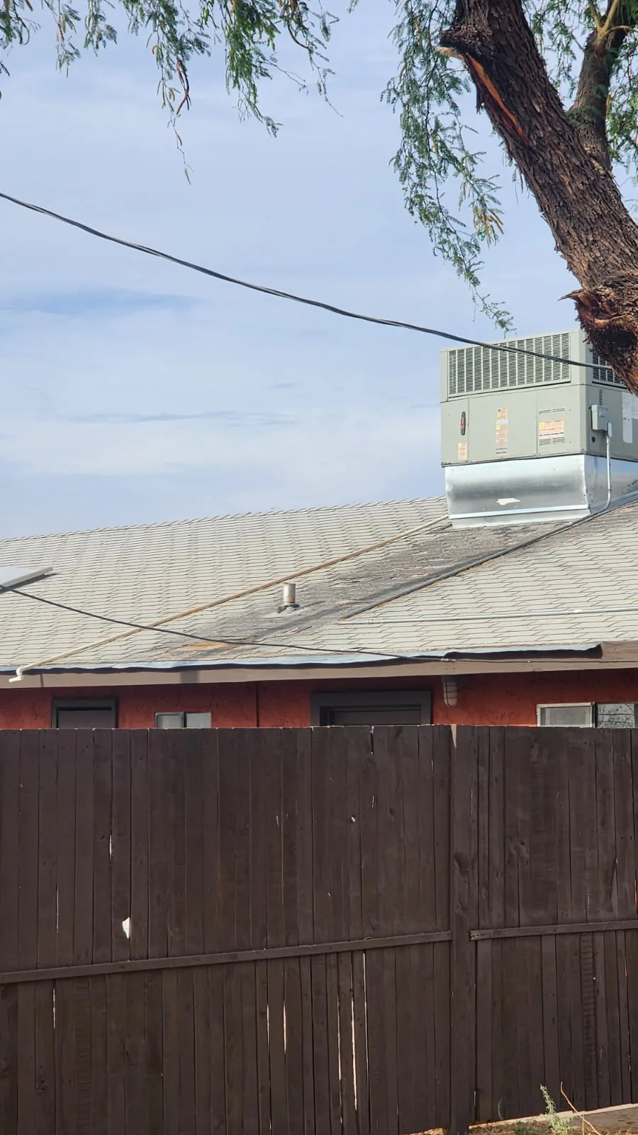 Aging shingle field near rooftop package unit in Tucson